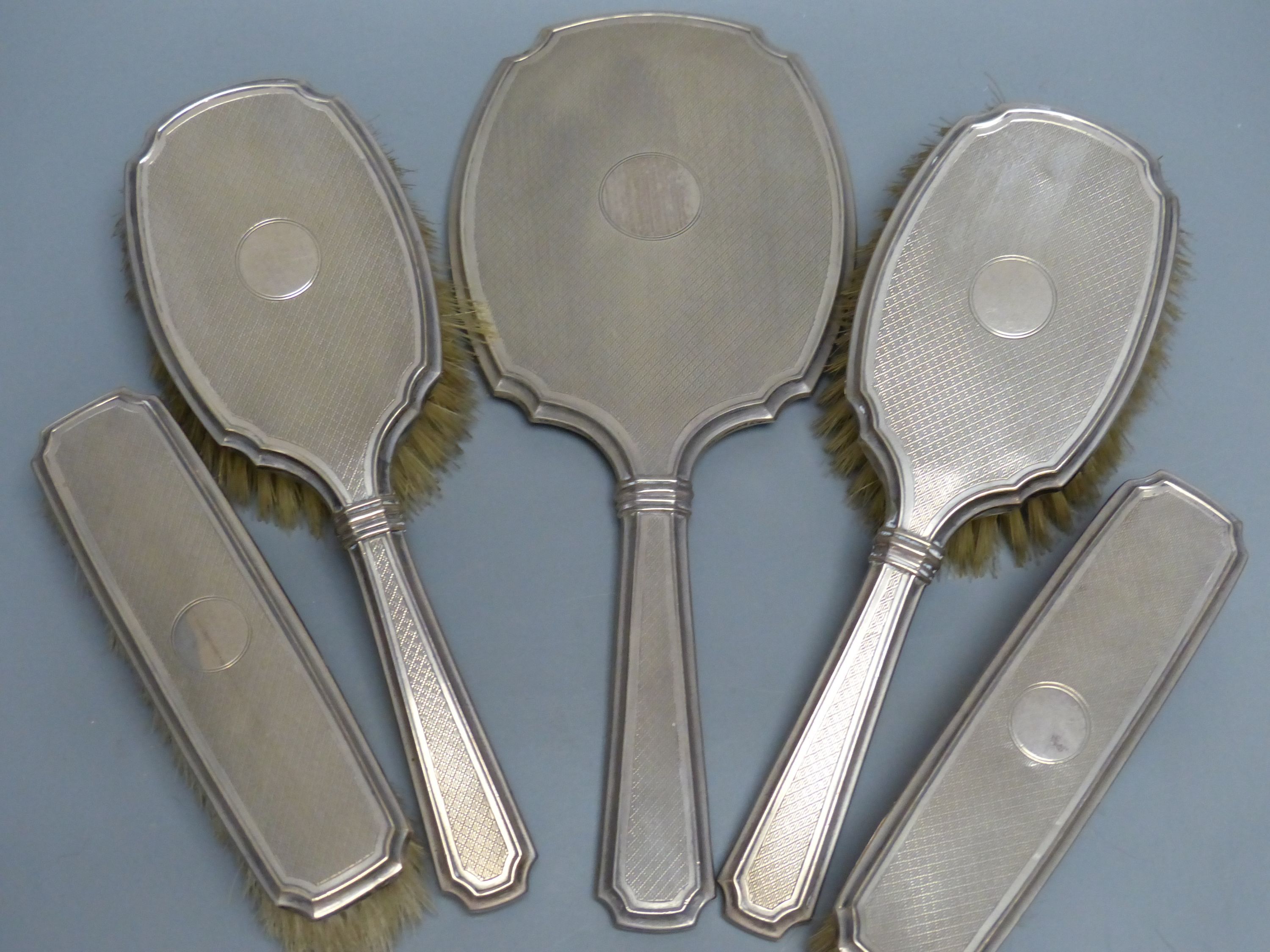 A six-piece engine-turned silver-mounted dressing table set, comprising two pairs of brushes, a comb and a hand mirror, Birmingham 1929